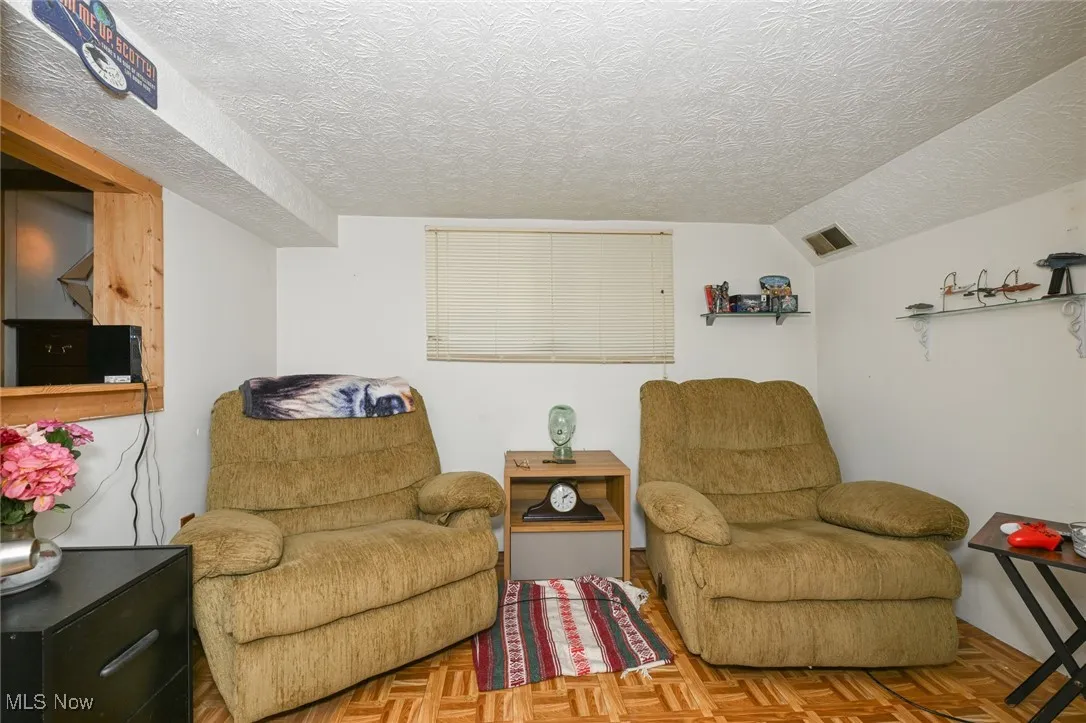 Sitting room featuring a textured ceiling and lofted ceiling