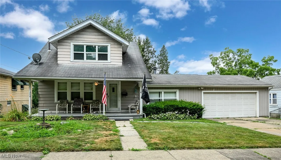 View of front of home featuring covered porch, a garage, concrete driveway, and a front lawn