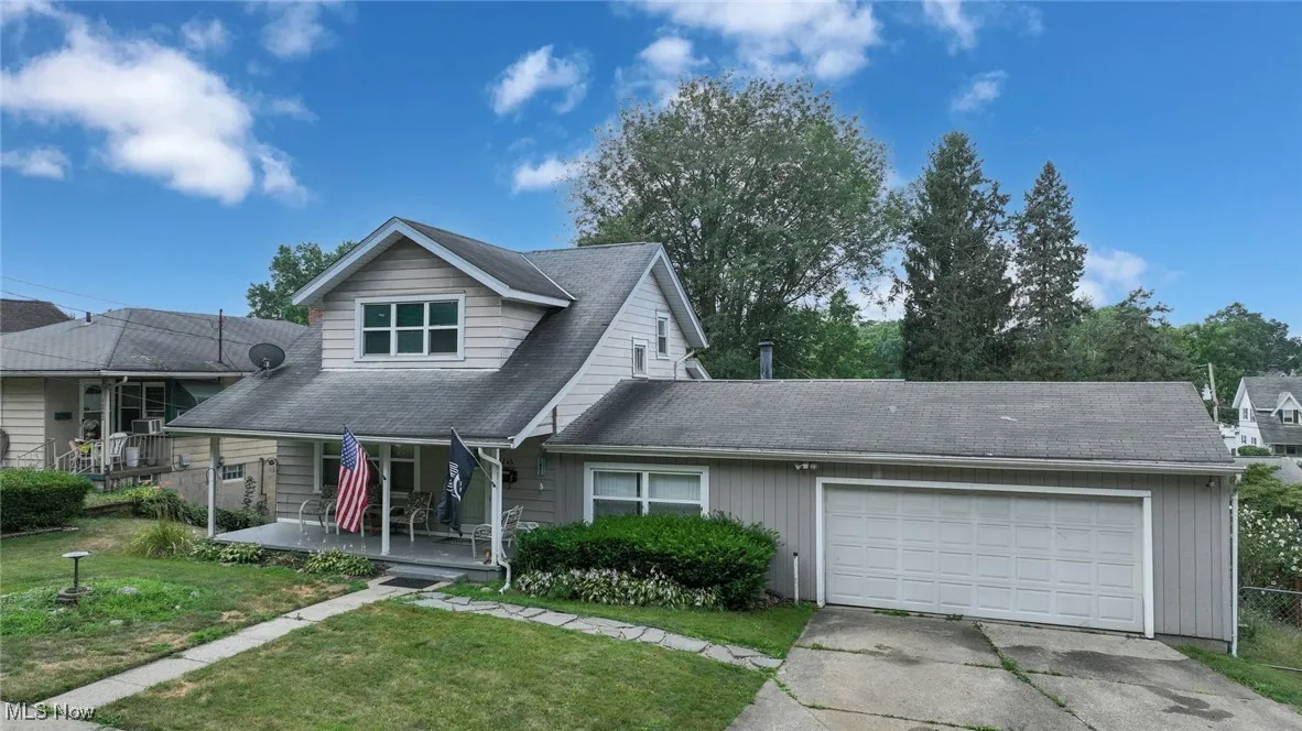 View of front of house featuring a porch, an attached garage, a front lawn, and driveway