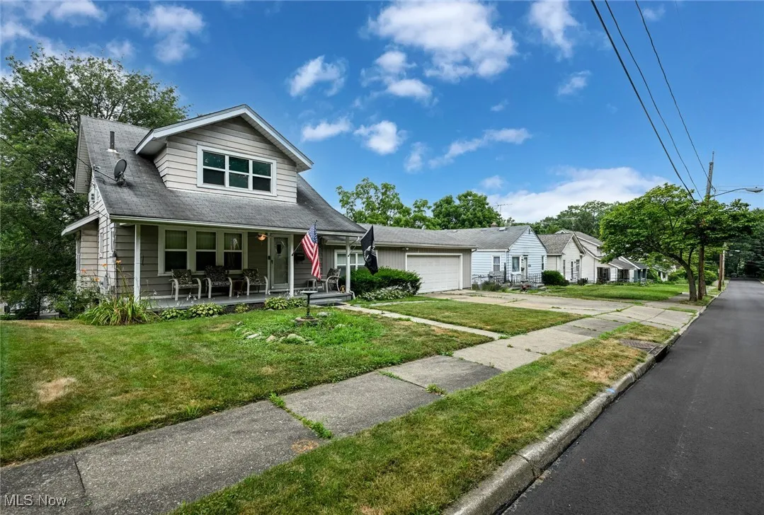 View of front of property with a porch, an attached garage, a front yard, and driveway