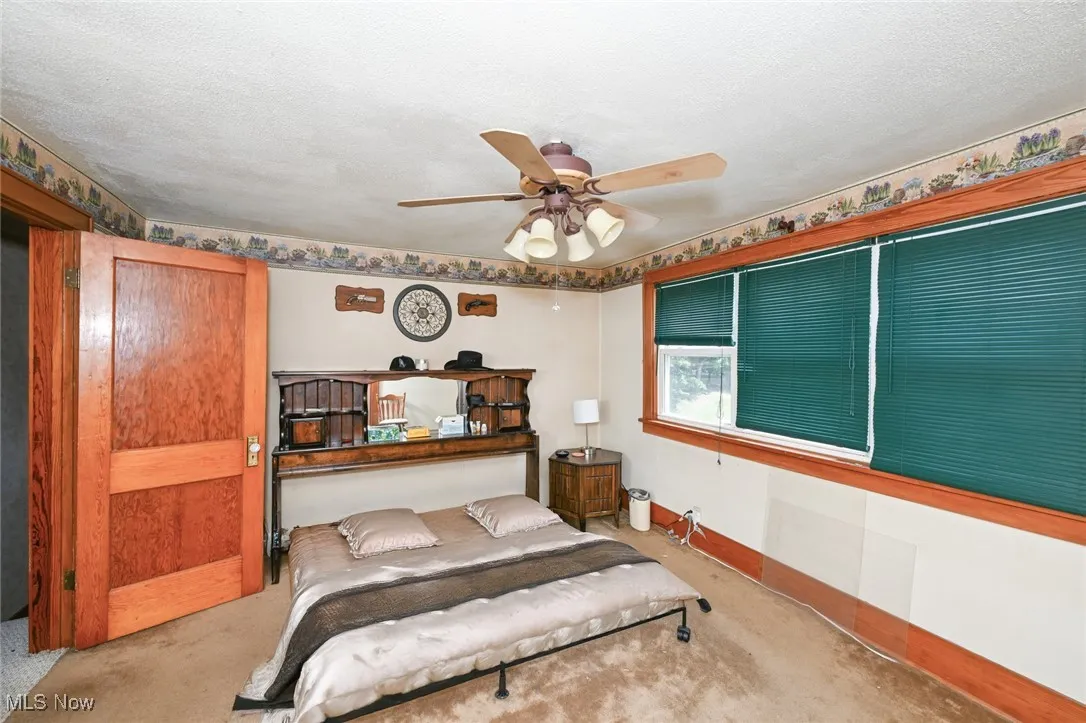 Carpeted bedroom with ceiling fan and baseboards