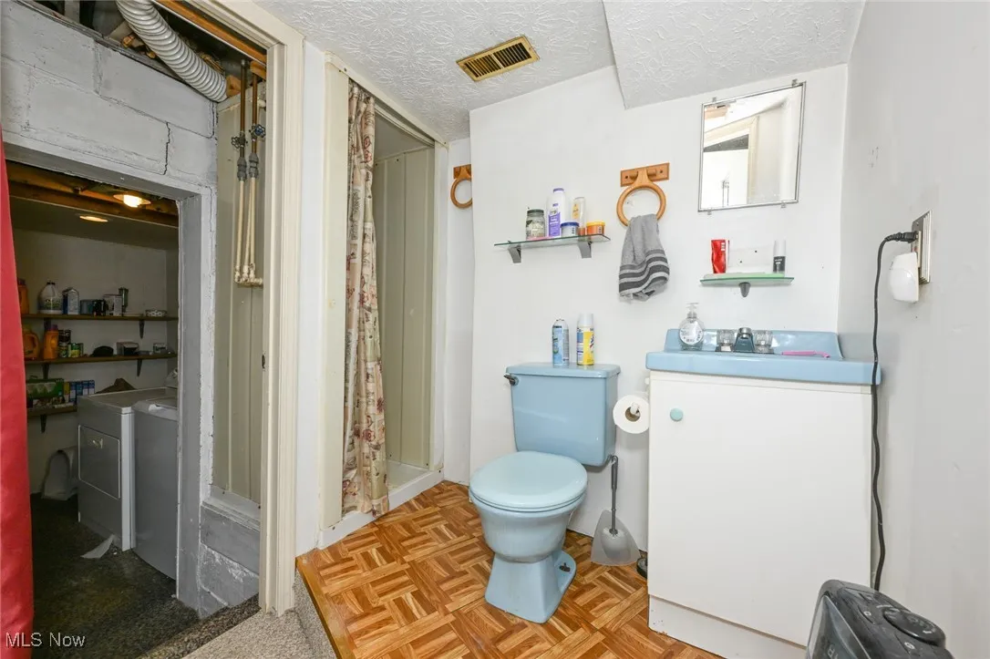 Full bath with separate washer and dryer, a shower with curtain, and a textured ceiling