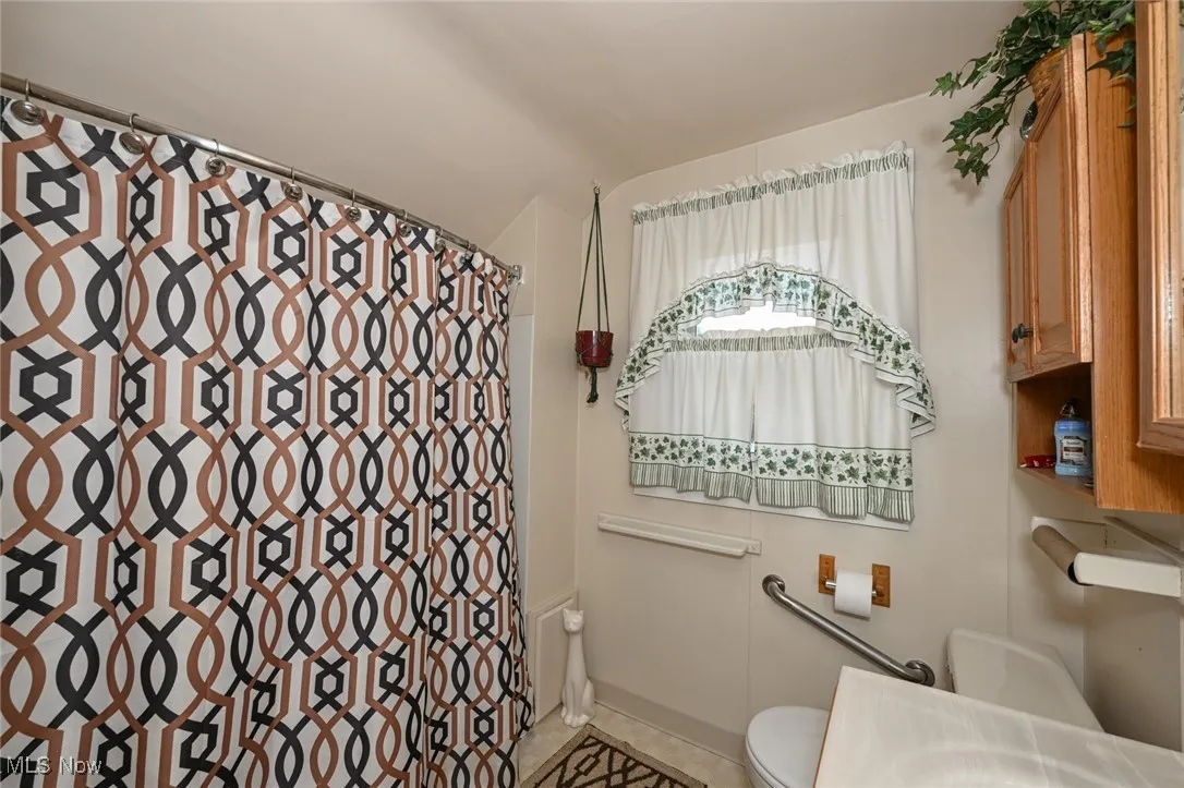 Bathroom featuring a shower with shower curtain and tile patterned flooring
