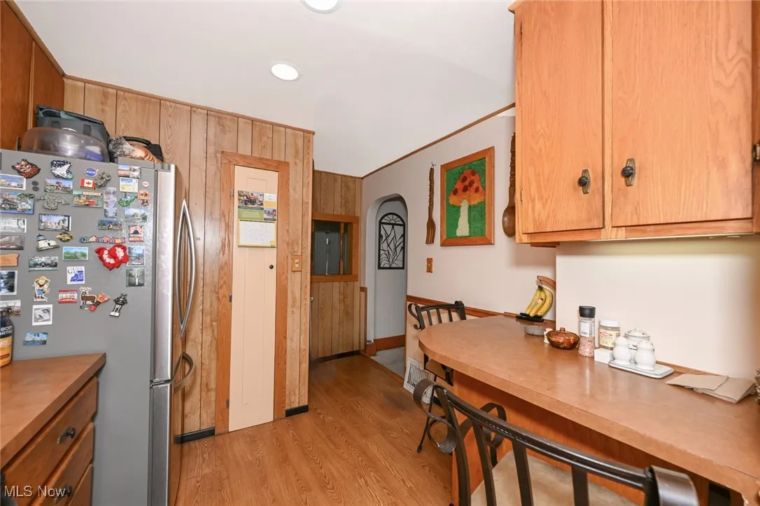 Kitchen featuring freestanding refrigerator, light wood-style floors, arched walkways, recessed lighting, and light countertops