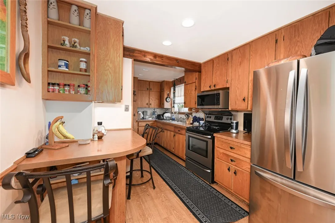 Kitchen featuring stainless steel appliances, light wood finished floors, brown cabinets, and recessed lighting