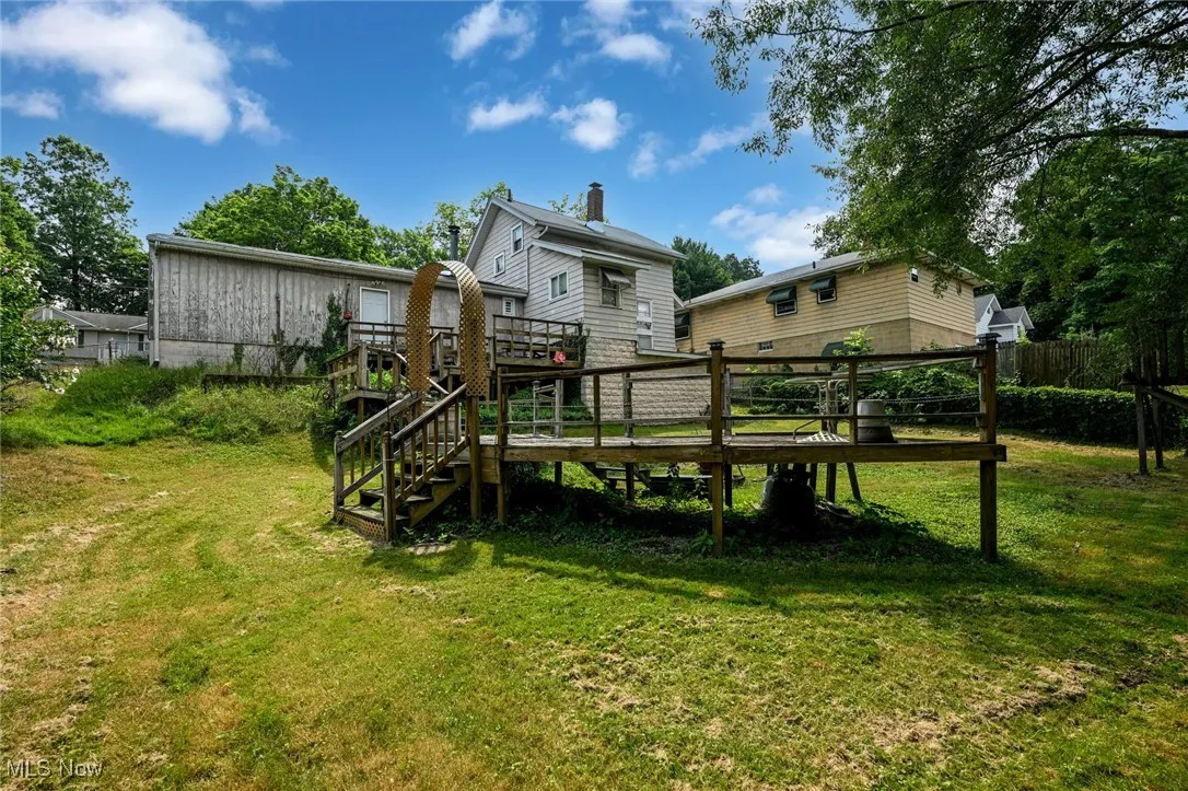 Back of house with a wooden deck, stairway, and a chimney