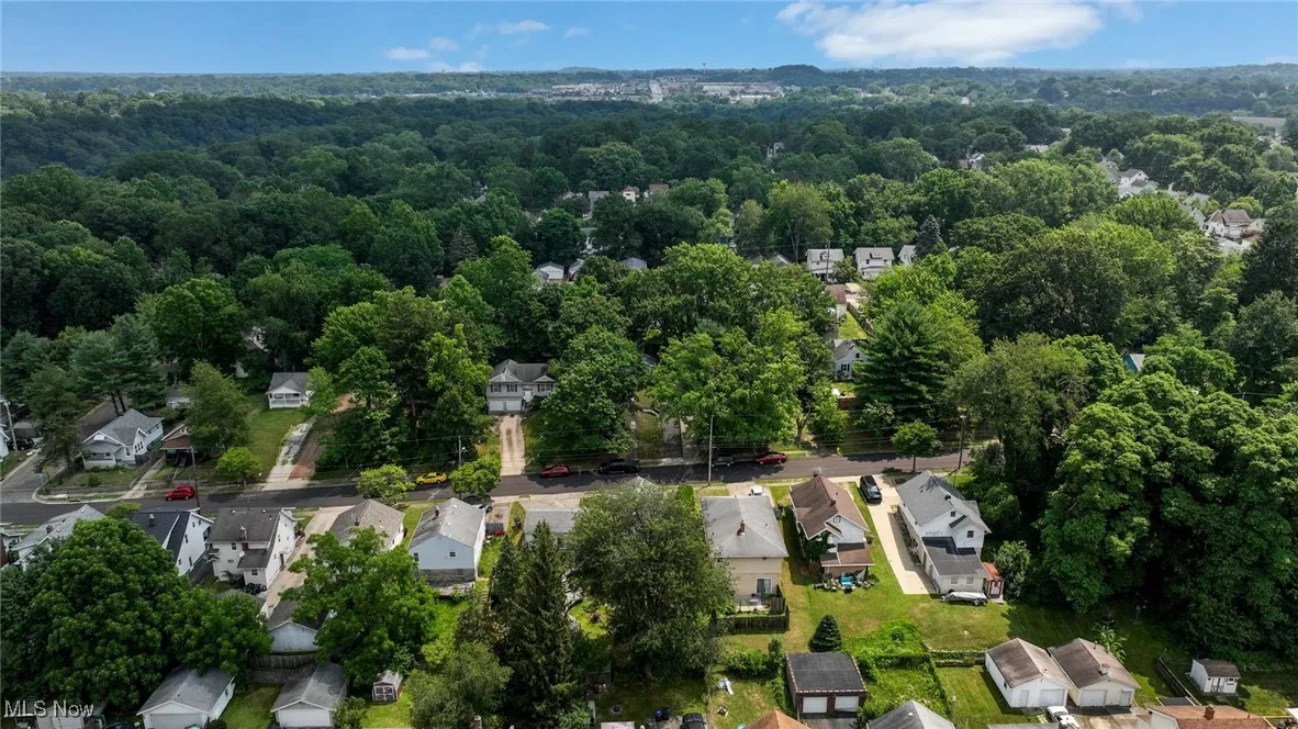 Aerial view of property's location featuring nearby suburban area and a forest