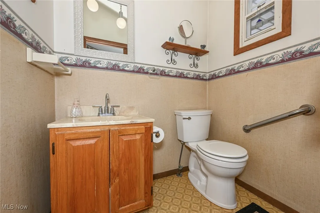 Half bathroom featuring vanity, wainscoting, and tile patterned floors