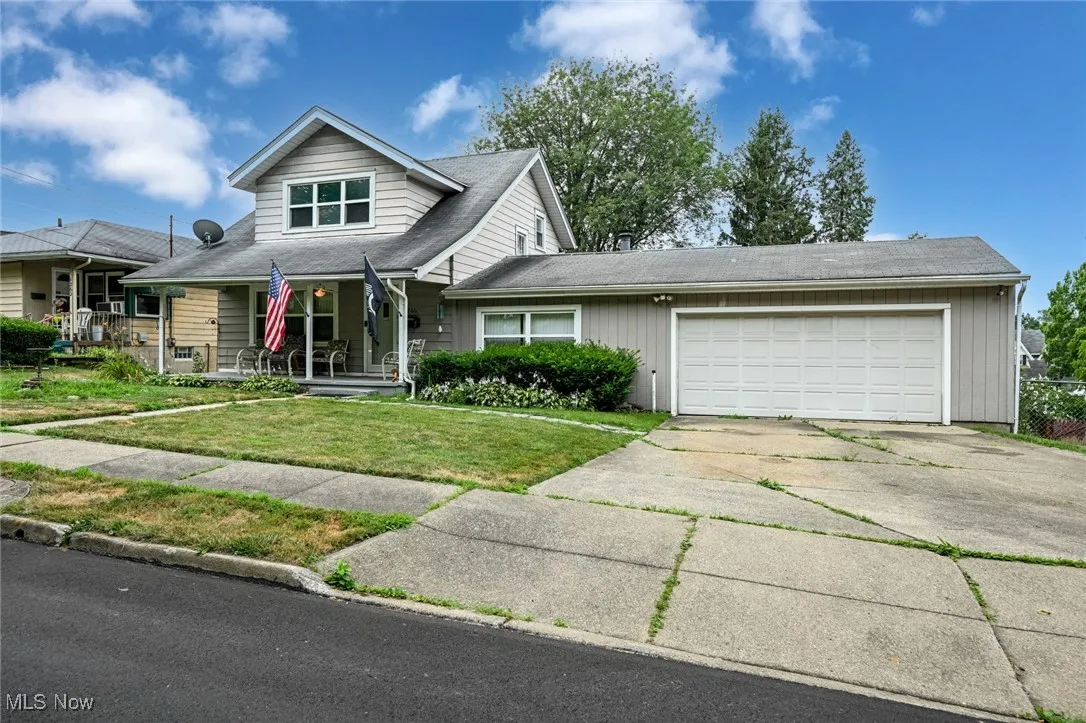 View of front of house with a garage, driveway, a front yard, and covered porch