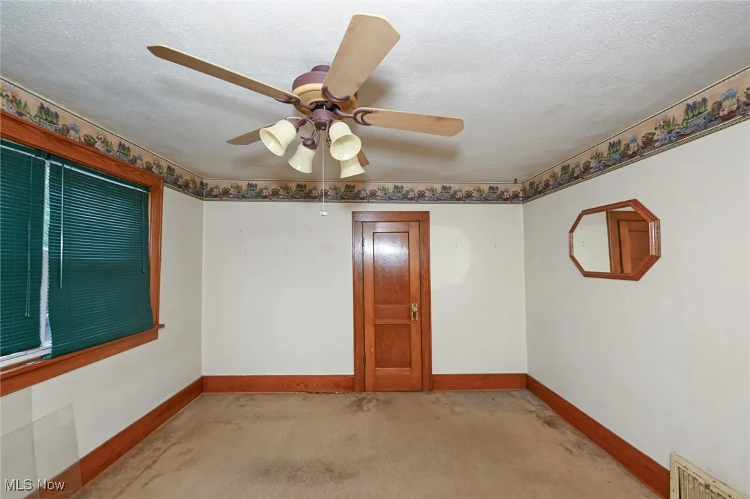 Unfurnished room with light carpet, ceiling fan, and a textured ceiling
