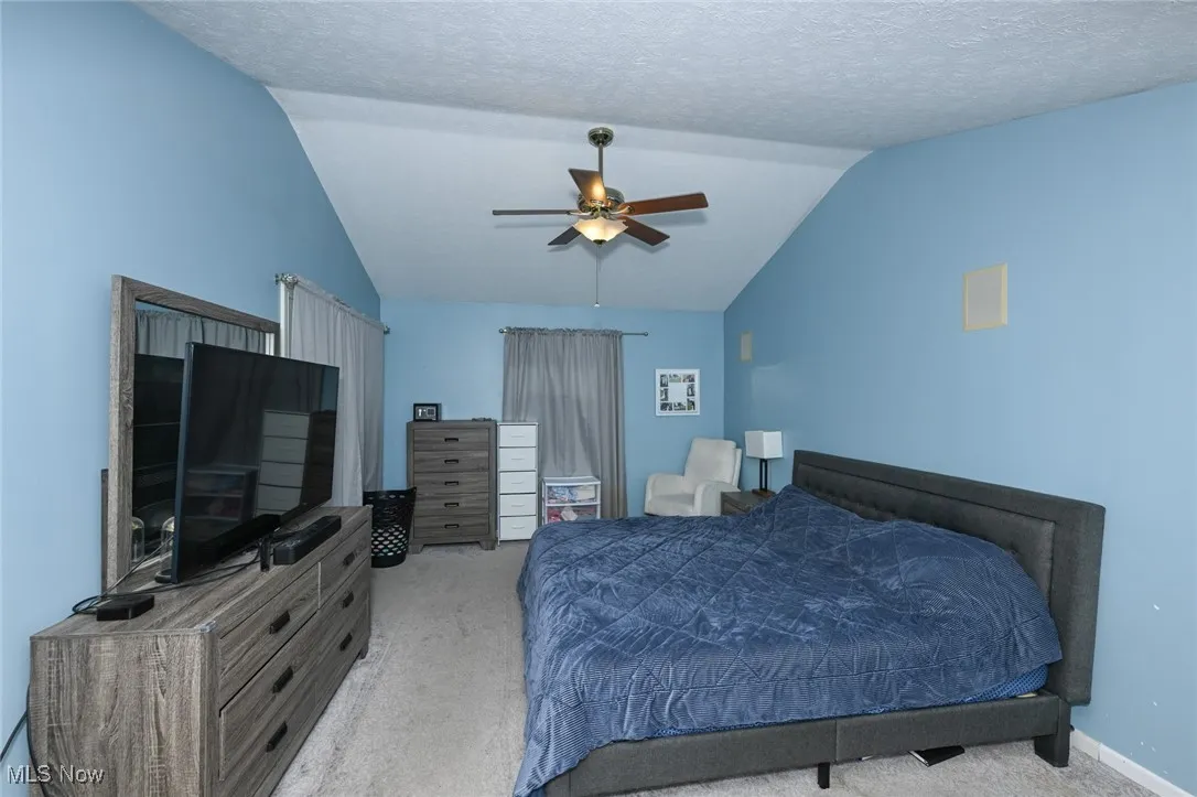 Bedroom featuring vaulted ceiling, carpet, and ceiling fan