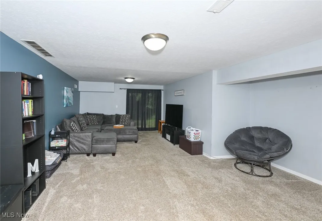 Carpeted living room with a textured ceiling and baseboards