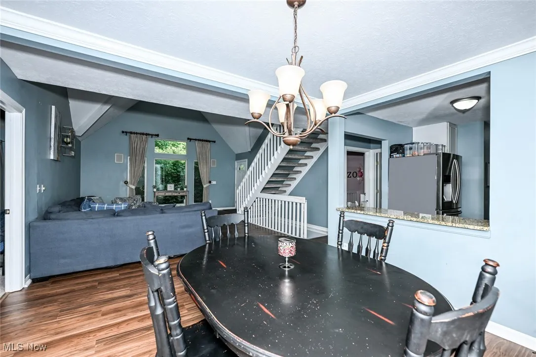 Dining space with a chandelier, wood finished floors, and stairs