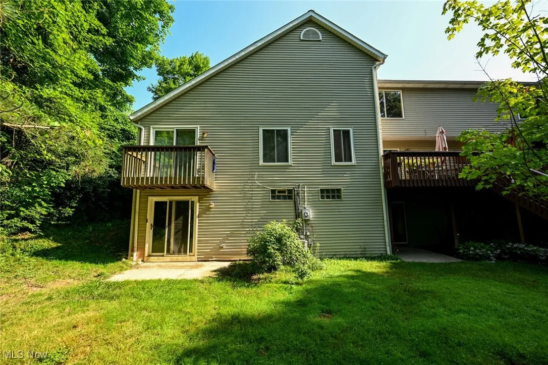 Rear view of property featuring a lawn and a deck