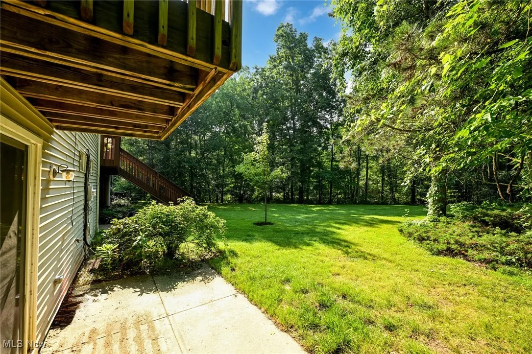 View of grassy yard with stairs and a patio area