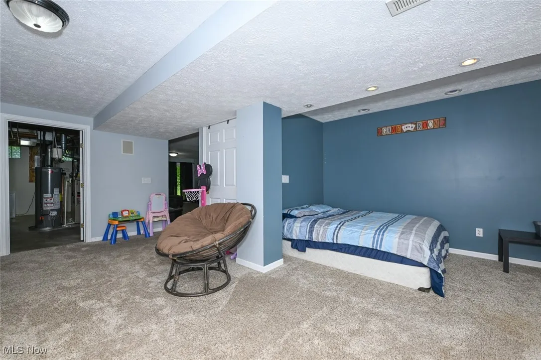 Carpeted bedroom featuring gas water heater, a textured ceiling, and recessed lighting