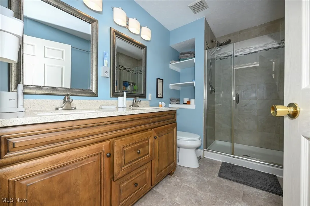 Full bath featuring double vanity and a stall shower