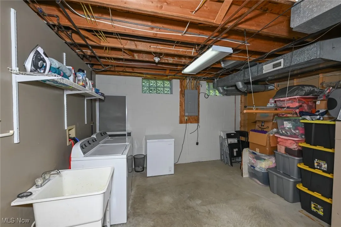 Below grade area with washer and dryer, electric panel, and refrigerator