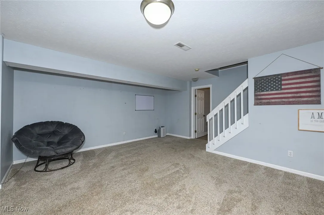 Finished basement featuring stairway, carpet, and a textured ceiling