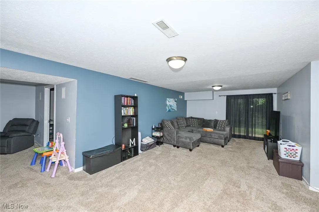 Carpeted living room featuring baseboards and a textured ceiling