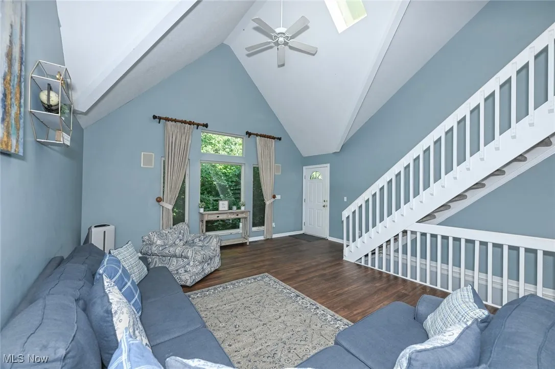 Living area featuring wood finished floors, a ceiling fan, vaulted ceiling, and a skylight