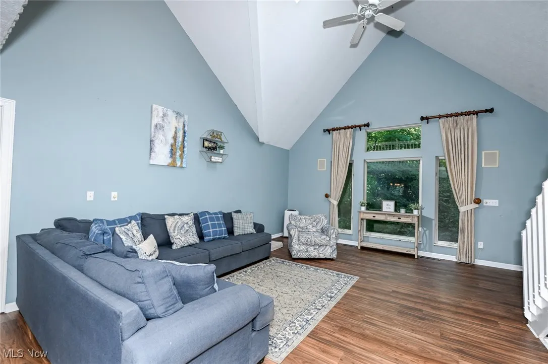 Living room with wood finished floors, high vaulted ceiling, and a ceiling fan