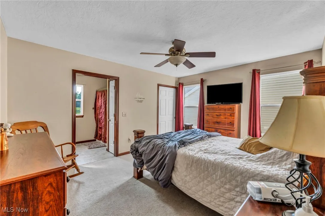 Bedroom featuring a ceiling fan, light colored carpet, and a textured ceiling