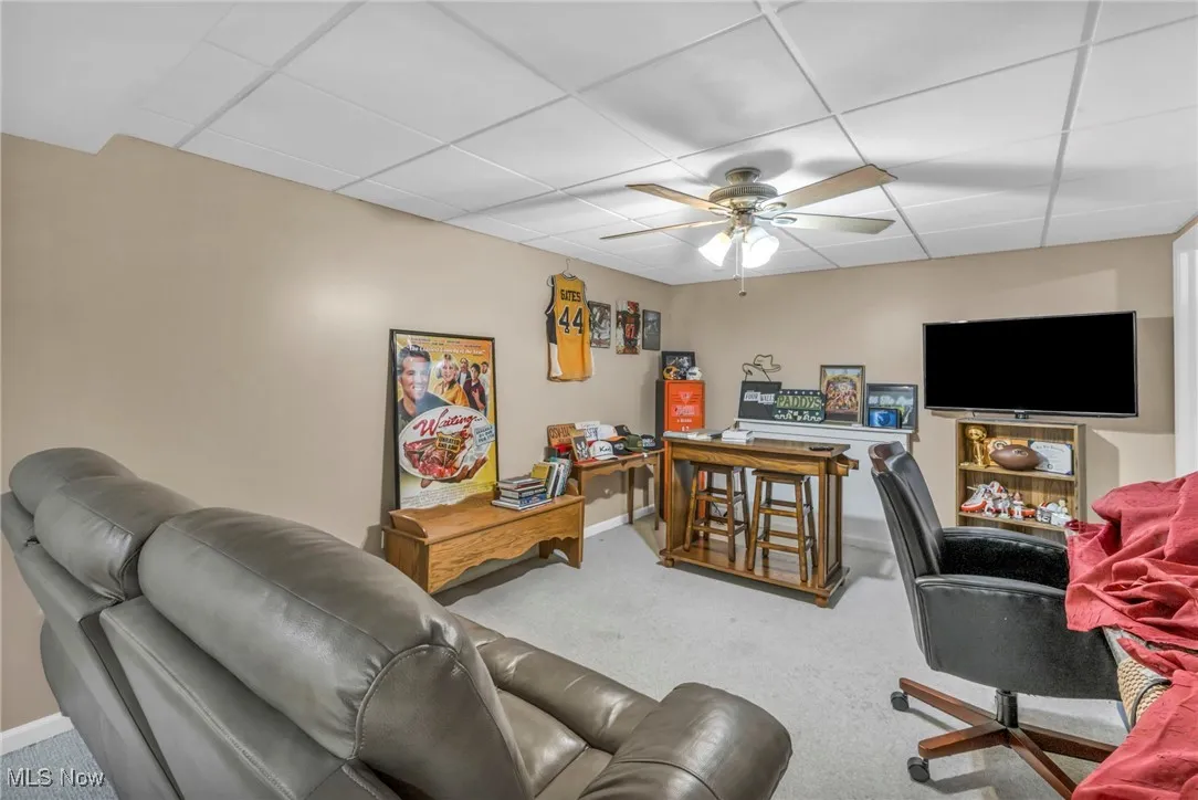 Carpeted living room with a ceiling fan and a paneled​​‌​​​​‌​​‌‌​‌‌​​​‌‌​‌​‌​‌​​​‌​​ ceiling