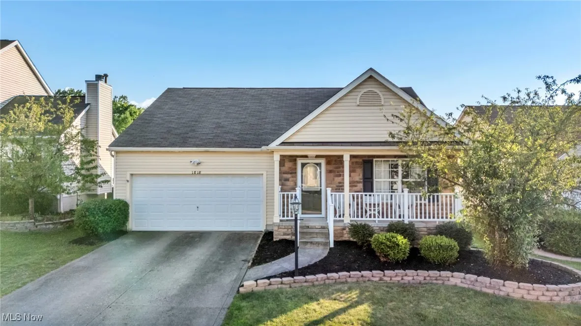 View of front of house with a porch, an attached garage, concrete driveway, a front lawn, and a shingled roof