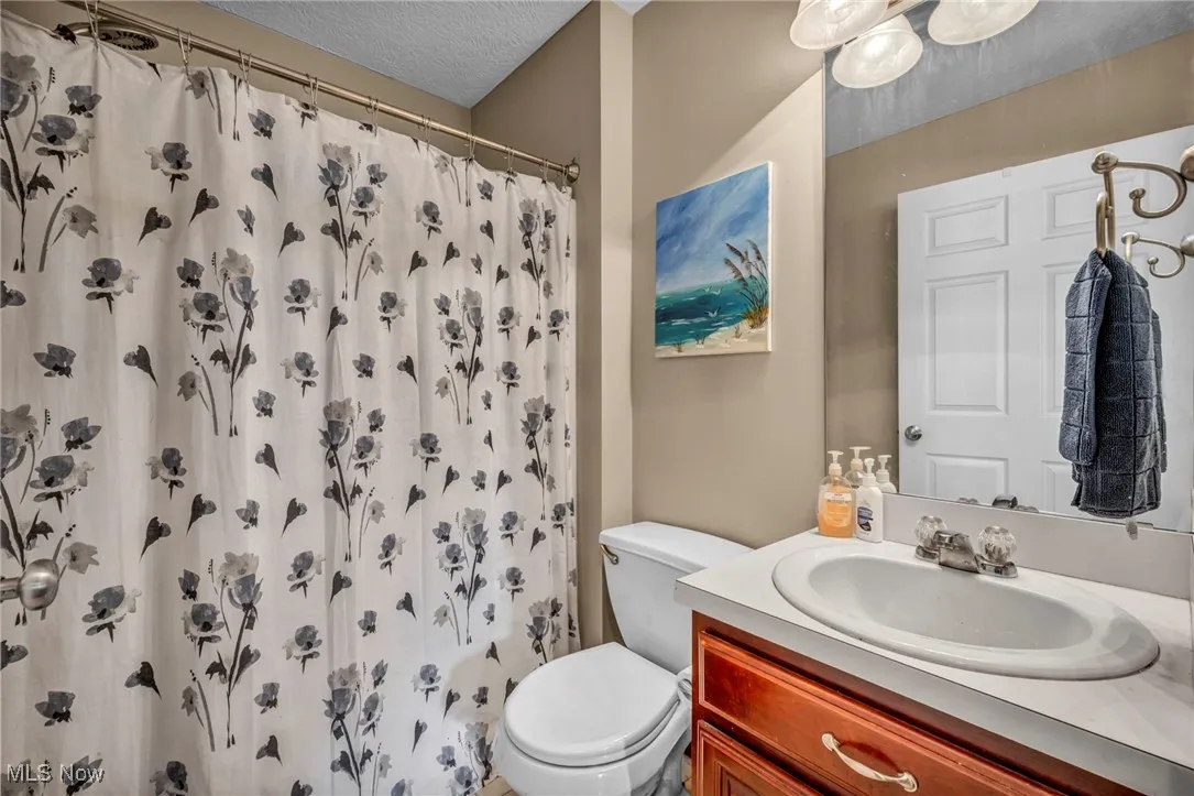 Bathroom with vanity, curtained shower, and a textured ceiling