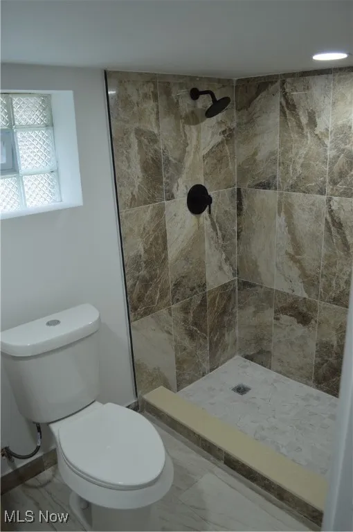 Full bathroom featuring tiled shower and marble finish floors