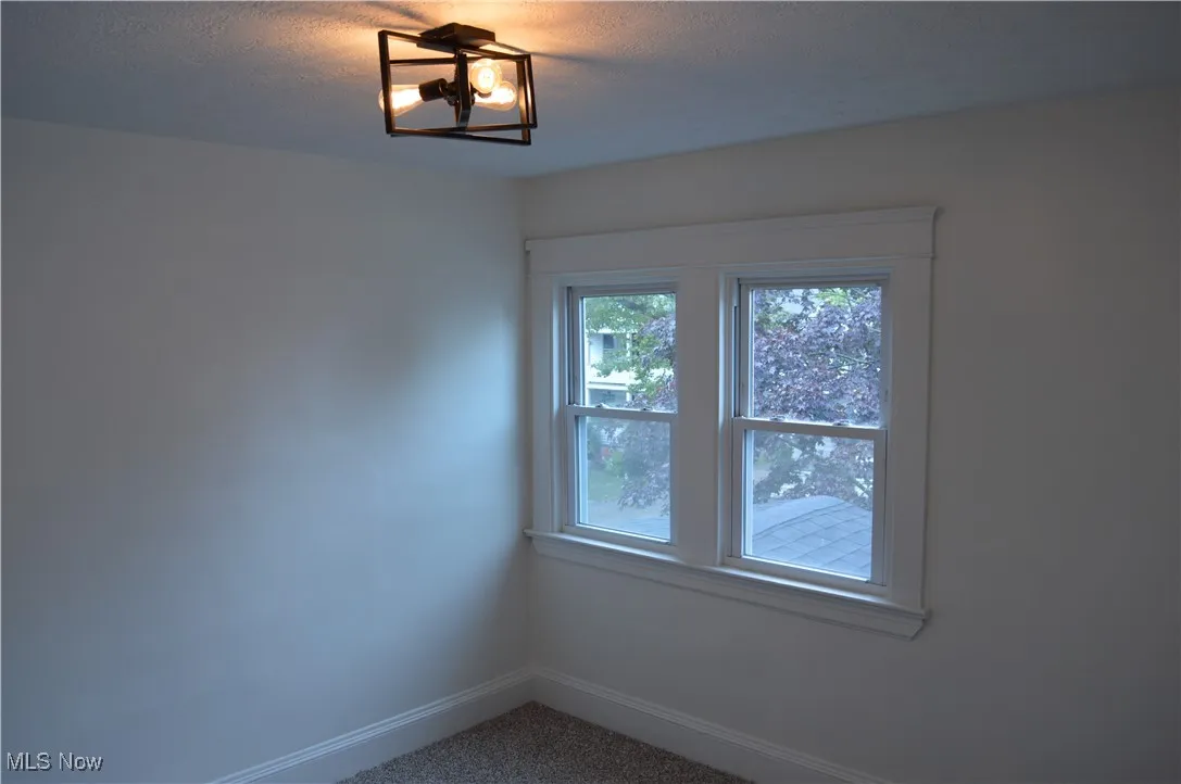 Carpeted spare room featuring baseboards and a textured ceiling