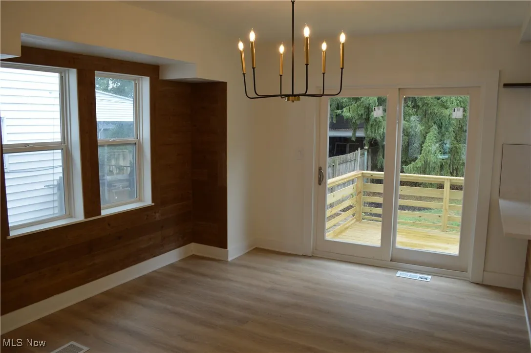 Unfurnished dining area featuring a chandelier and wood finished floors