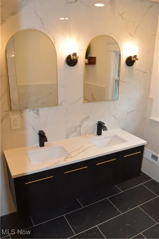 Full bathroom featuring tile walls, double vanity, and backsplash