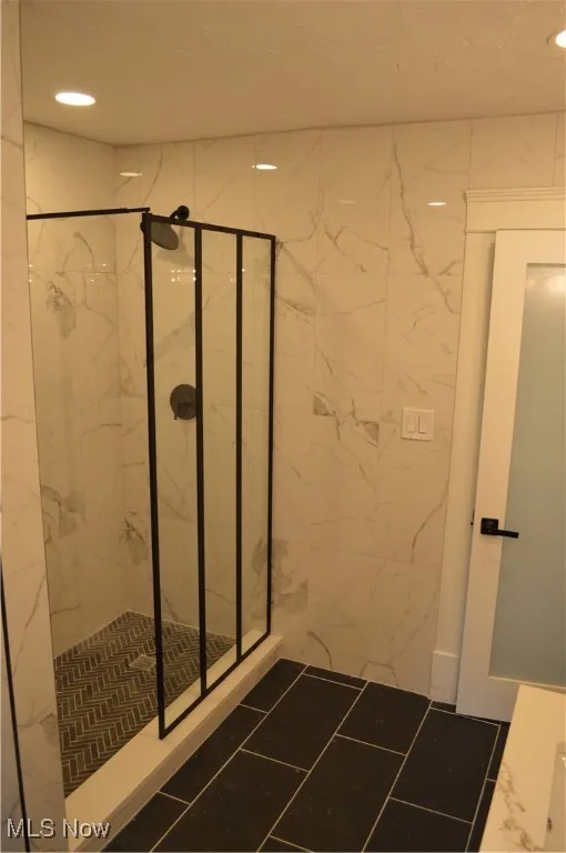 Full bathroom featuring a marble finish shower, recessed lighting, and marble look tile flooring