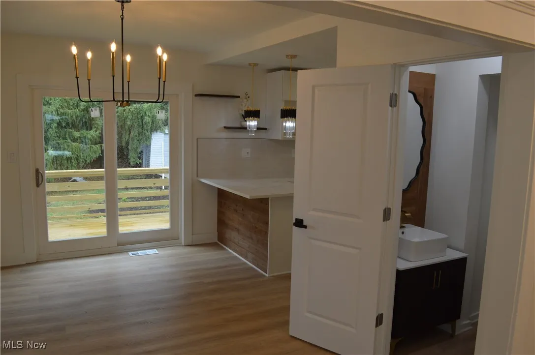 Kitchen with wood finished floors, backsplash, a chandelier, and hanging light fixtures