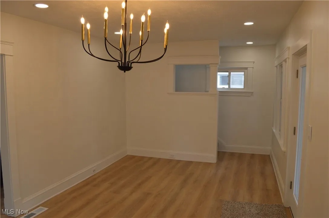 Unfurnished room featuring light wood-style flooring, recessed lighting, and a chandelier