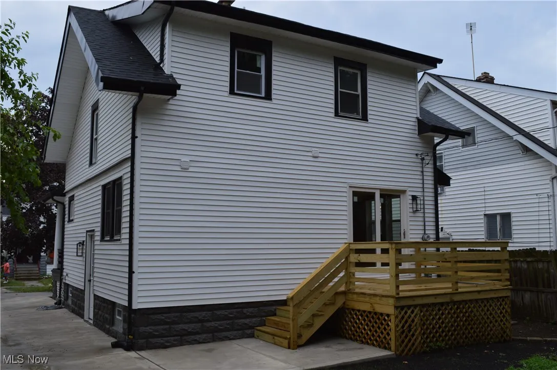 Back of property with a deck and roof with shingles