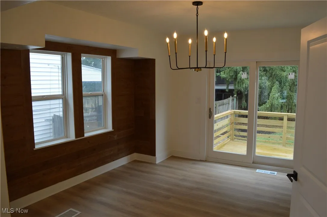 Unfurnished dining area with a chandelier and wood finished floors