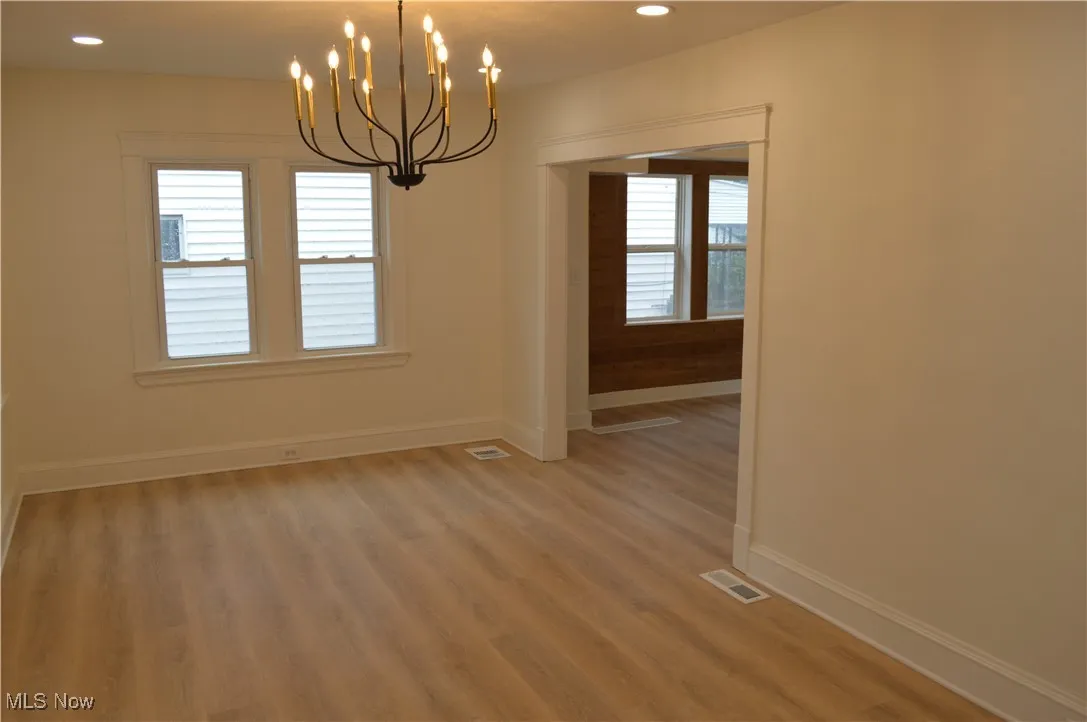 Empty room featuring light wood-style floors, a chandelier, and recessed lighting