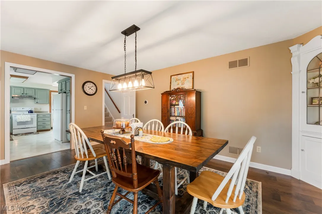Dining area with stairway and dark wood-style flooring