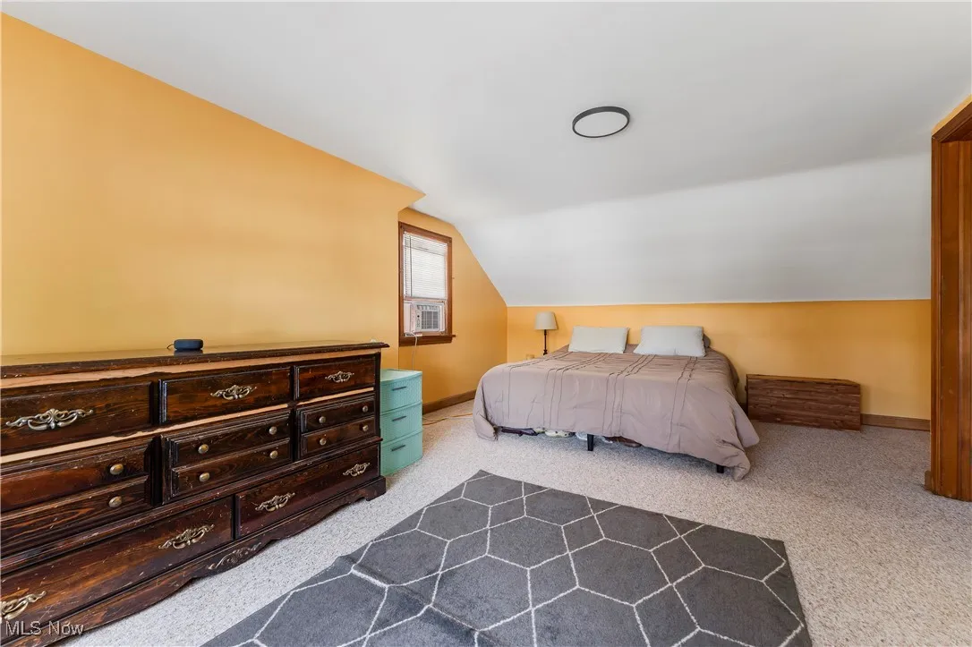 Bedroom featuring lofted ceiling, dark colored carpet, and cooling unit