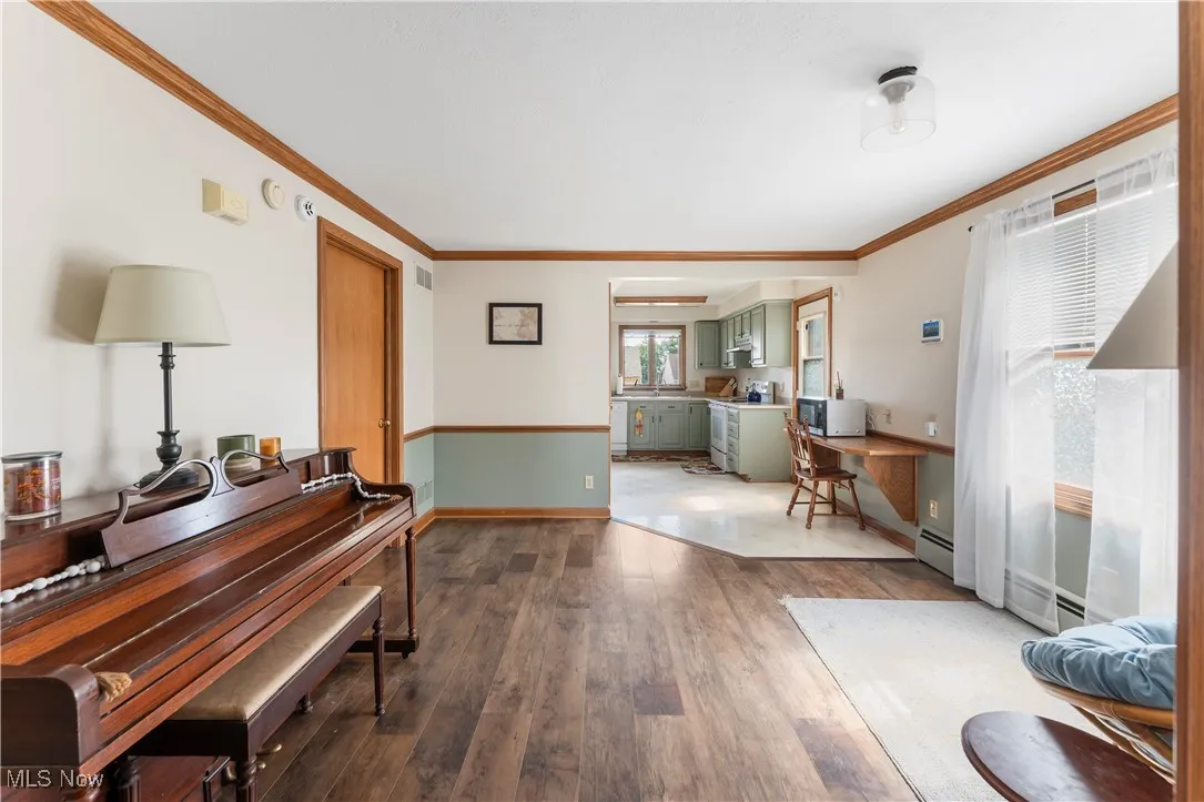 Living area featuring hardwood / wood-style floors, crown molding, a desk, and a baseboard radiator