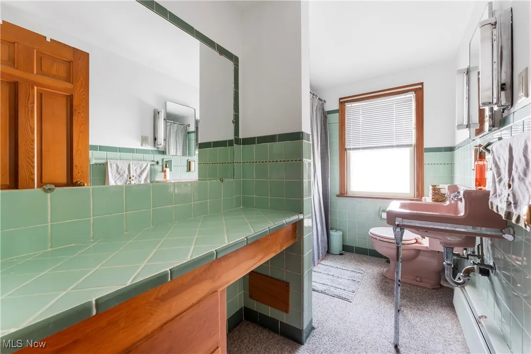 Full bath with tile walls, a wainscoted wall, and curtained shower