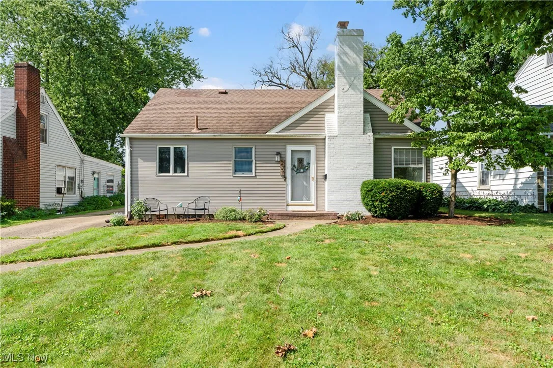 View of front facade featuring a front lawn and a chimney