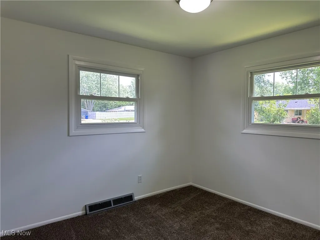Spare room with plenty of natural light and dark colored carpet