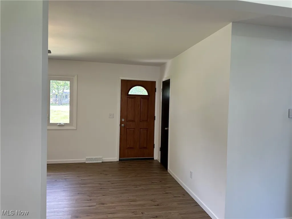 Foyer featuring dark wood-style flooring and baseboards