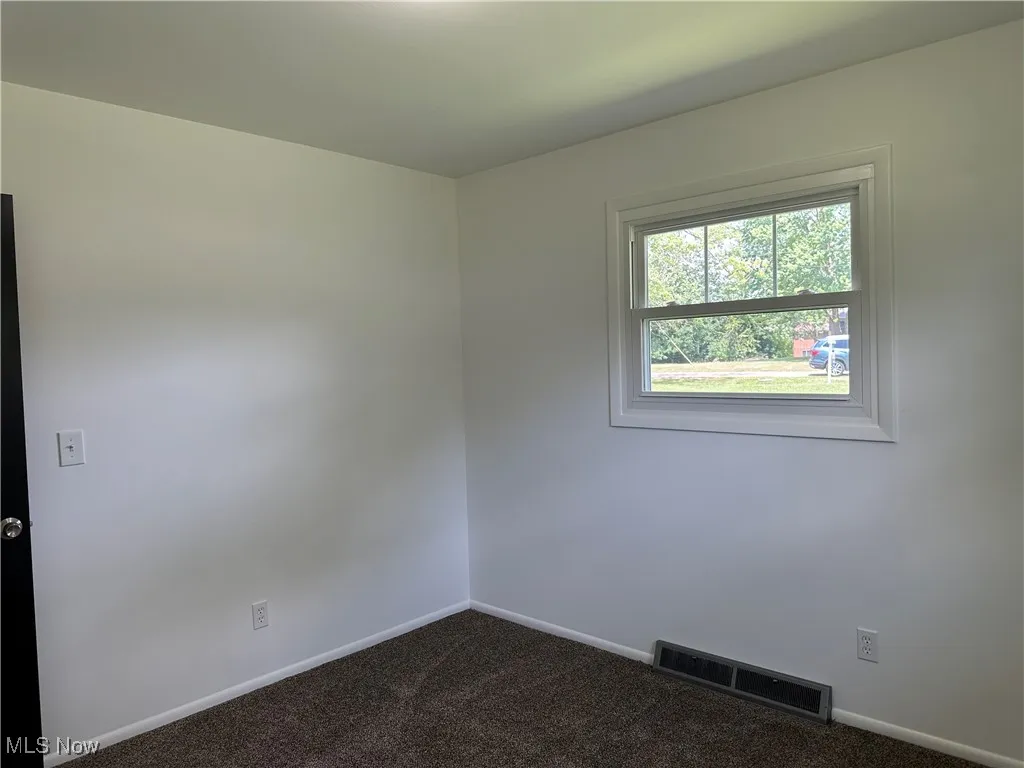 Empty room featuring dark carpet