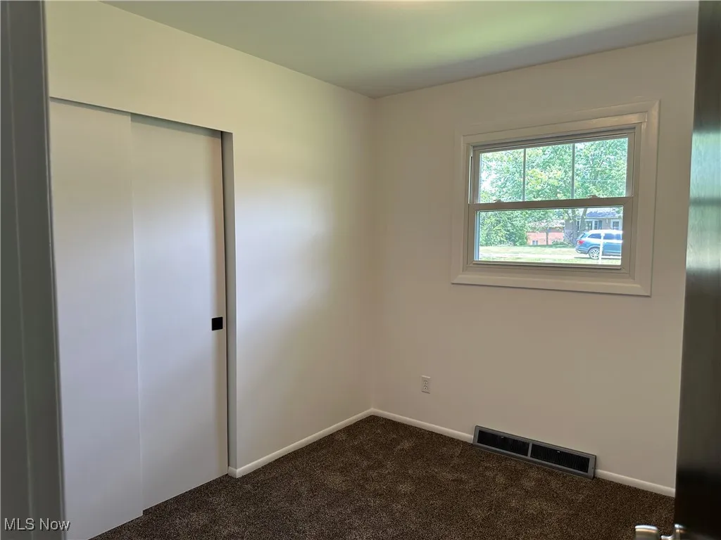 Unfurnished bedroom featuring dark carpet and a closet