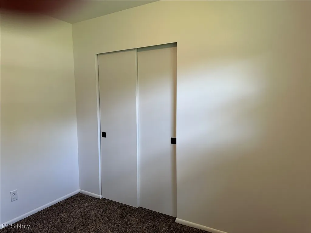 Unfurnished bedroom with dark carpet and a closet